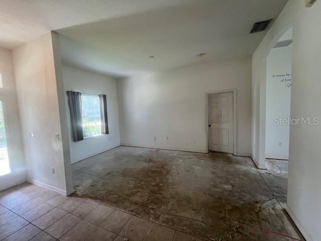 An empty room features tile flooring near the entrance and a large, unfinished concrete area — 5566 LAVENDER AVENUE, NORTH PORT, FL
