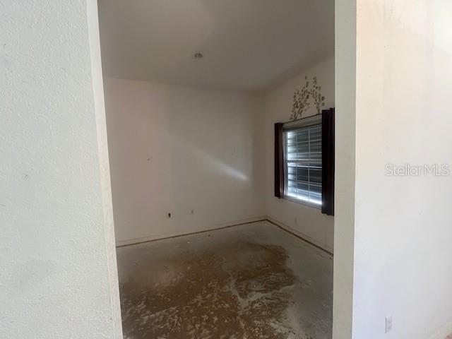 An empty room with white walls, a window with dark curtains, and a concrete floor — 5566 LAVENDER AVENUE, NORTH PORT, FL