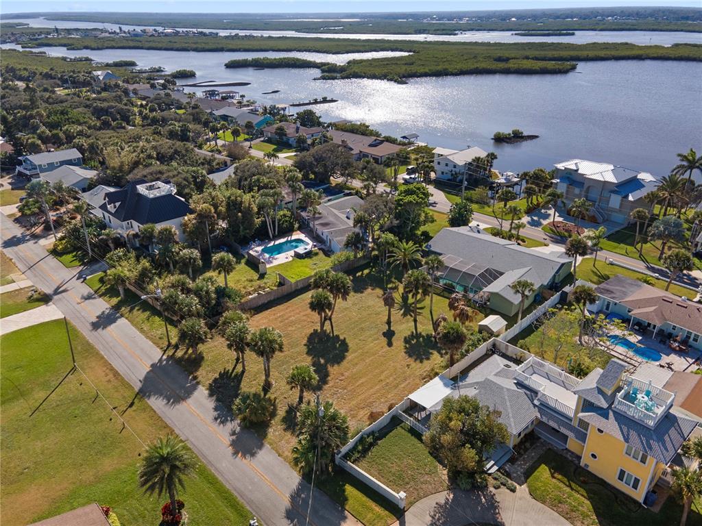 An aerial view shows a vacant residential lot situated between houses near a coastal waterway — 4216 CARDINAL BOULEVARD, PORT ORANGE, FL
