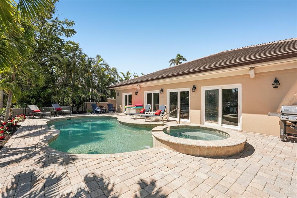 A backyard patio features a swimming pool, a raised spa, and lounge chairs by the house — 85 S POLK DRIVE, SARASOTA, FL