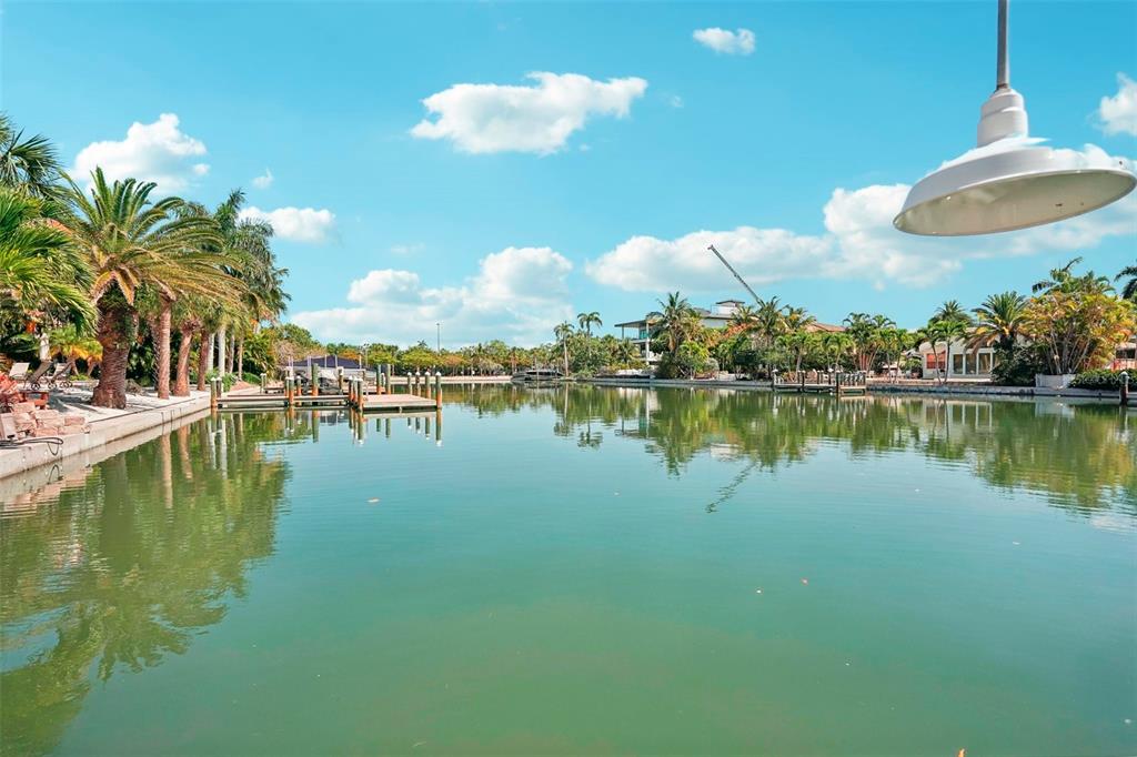 A view of a calm canal lined with palm trees, boat docks, and residential homes — 85 S POLK DRIVE, SARASOTA, FL