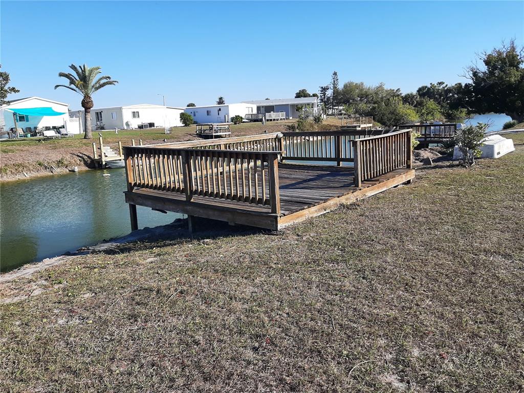 A wooden deck with railings overlooks a canal near several mobile homes — 1347 FLAMINGO DRIVE, ENGLEWOOD, FL