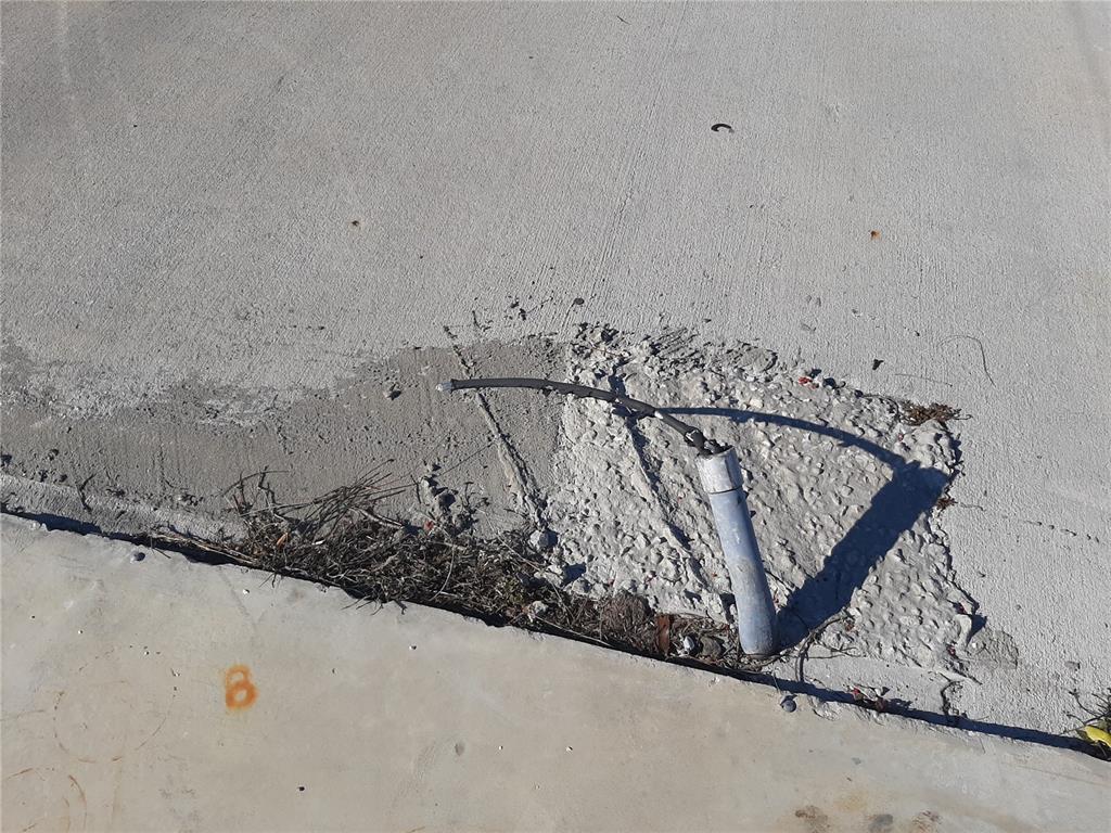 A black cable extends from a metal conduit embedded in a patch of concrete — 1347 FLAMINGO DRIVE, ENGLEWOOD, FL