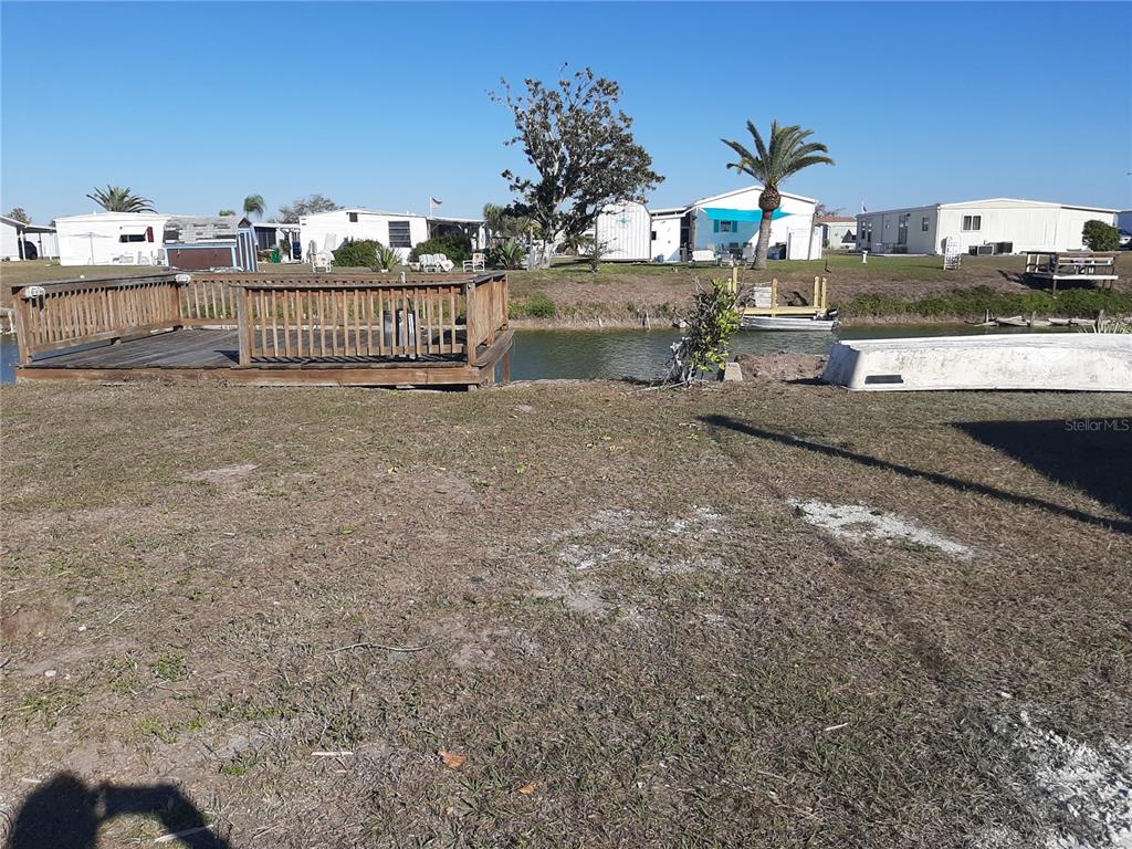 A wooden deck overlooks a narrow canal with mobile homes in the background — 1347 FLAMINGO DRIVE, ENGLEWOOD, FL
