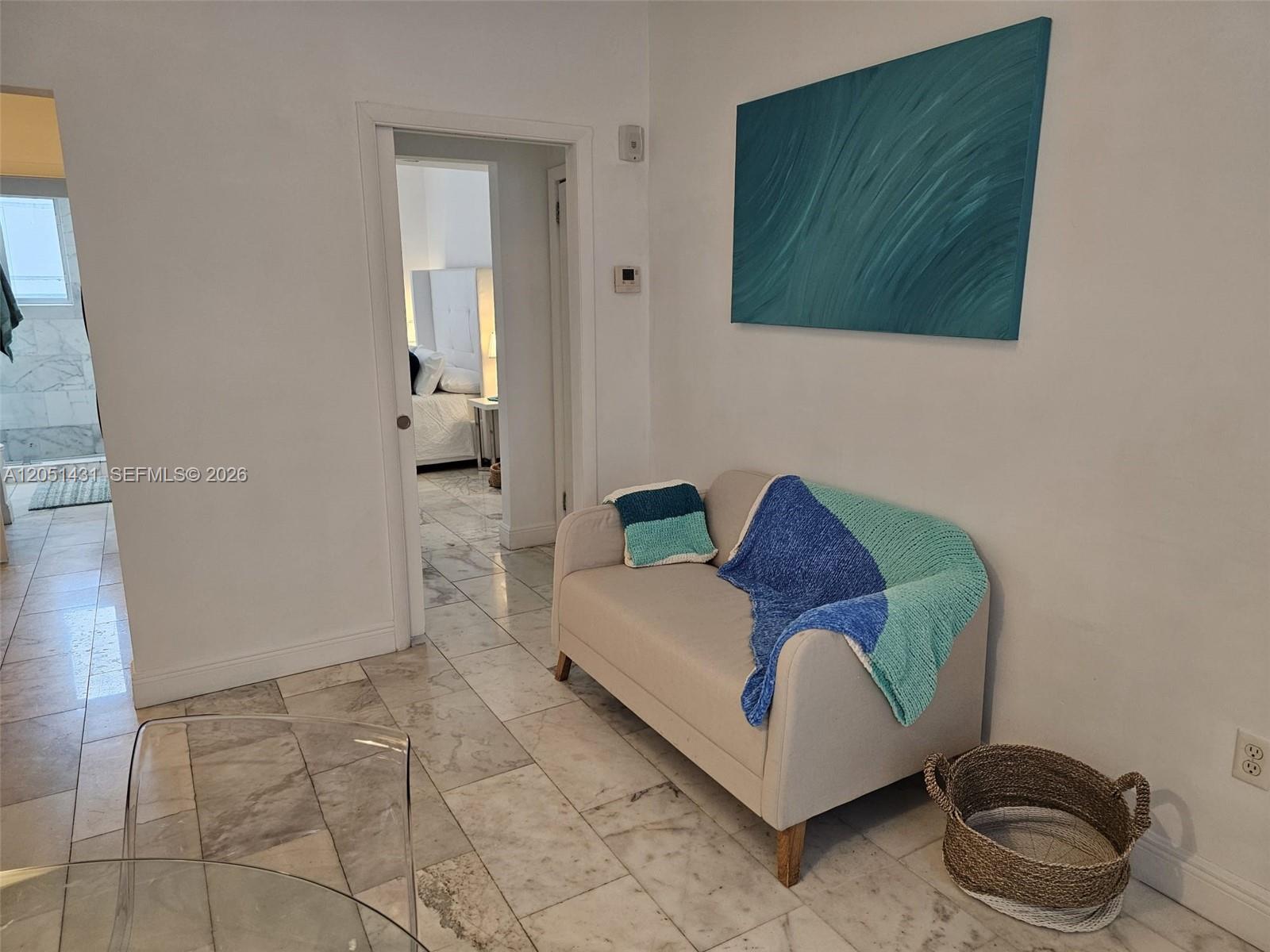 A small beige loveseat sits on a marble floor in a room with white walls — 918 Jefferson Ave # 8, Miami Beach FL 33139, MIAMI BEACH, FL