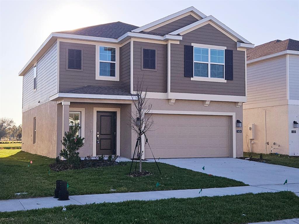 A two-story house with a beige stucco lower level, brown siding upper level, and garage — 1454 AUSTIN ST, WINTER HAVEN, FL