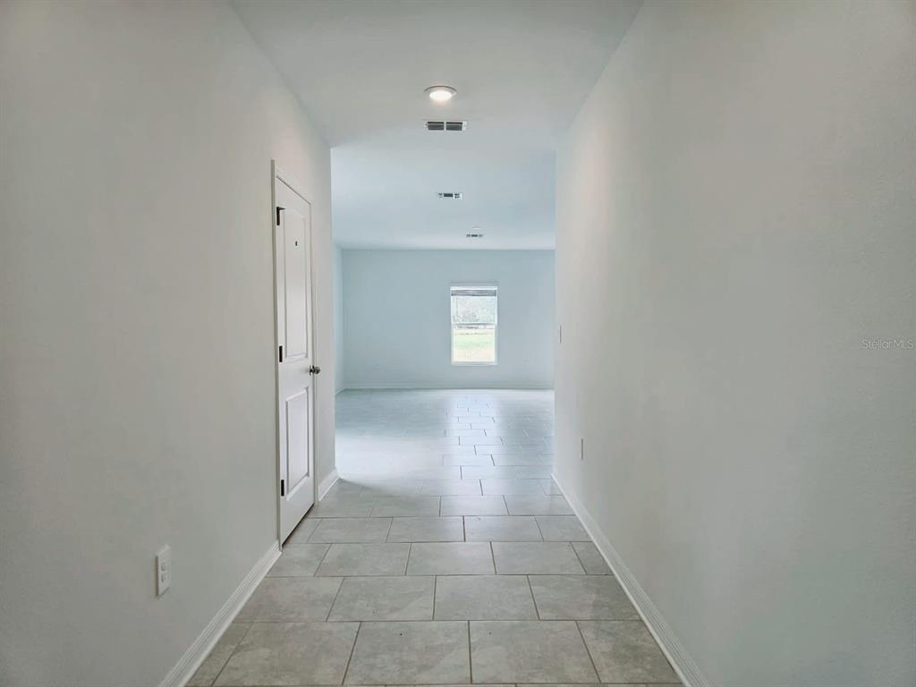 A tiled hallway leads to an open living area with a single window — 1454 AUSTIN ST, WINTER HAVEN, FL