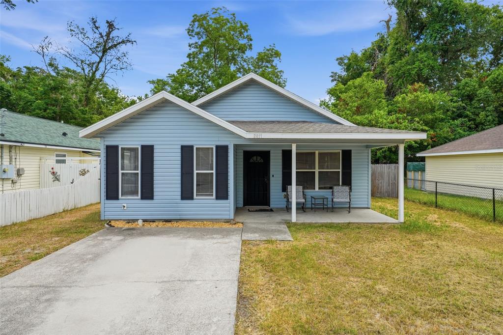 A light blue, single-story house with a front porch, concrete driveway, and black shutters — 2611 NW 1ST AVENUE, OCALA, FL