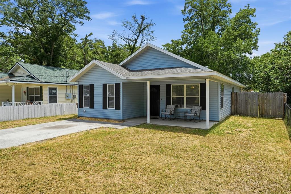 A blue, single-story house with a front porch and concrete driveway sits on a lawn — 2611 NW 1ST AVENUE, OCALA, FL