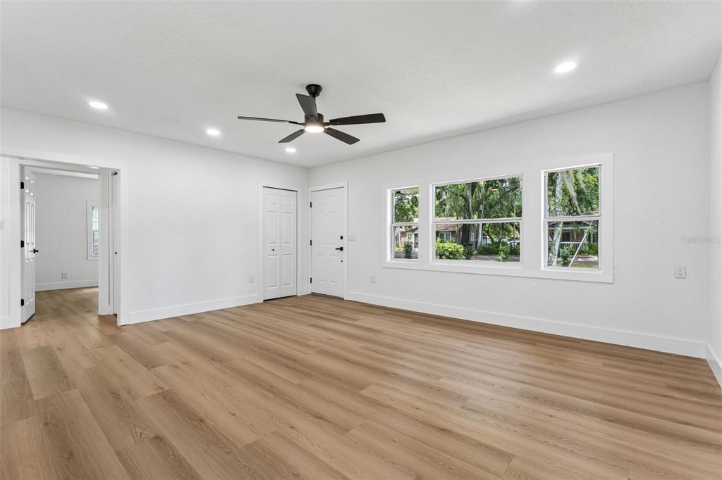 An empty room with white walls, light wood-look flooring, a ceiling fan, and large windows — 1910 CURRY FORD ROAD, ORLANDO, FL