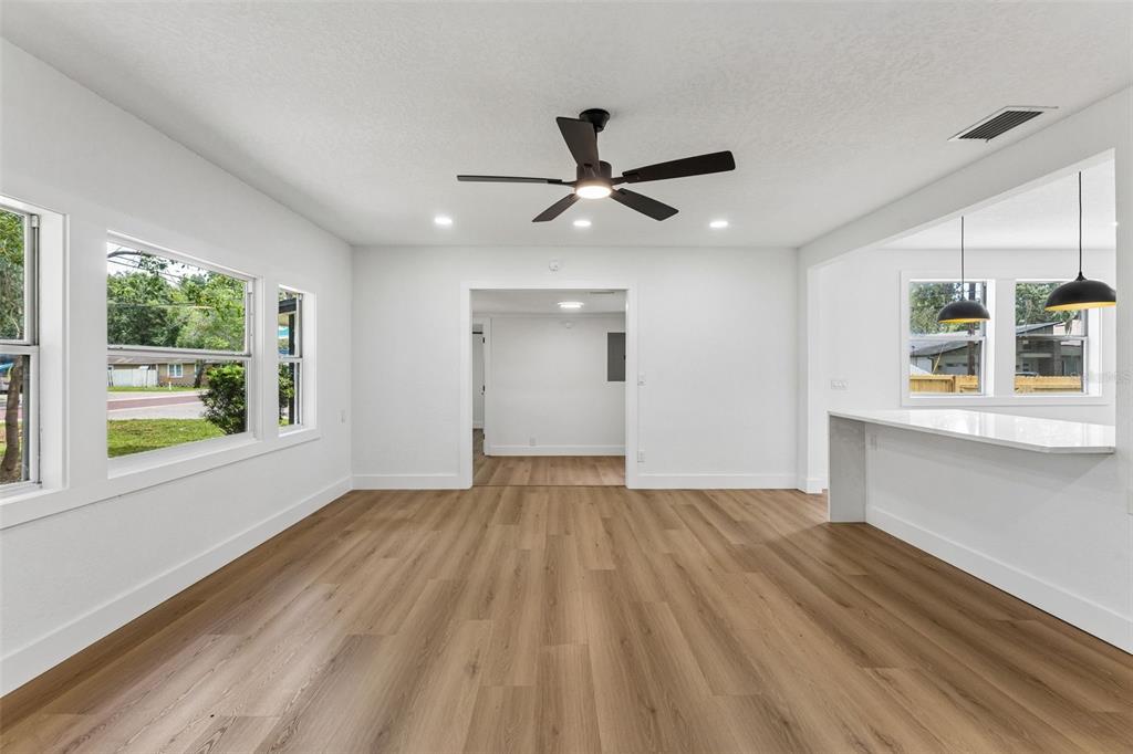 A bright living area features light wood-look flooring, a ceiling fan, and a kitchen pass-through — 1910 CURRY FORD ROAD, ORLANDO, FL