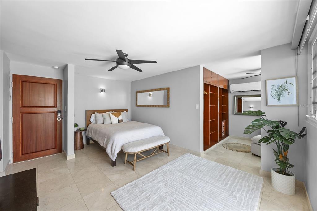 A bedroom features a bed, wooden wardrobe, ceiling fan, and tile flooring — 1126 ASHFORD AVENUE UNIT 88, SAN JUAN, PR