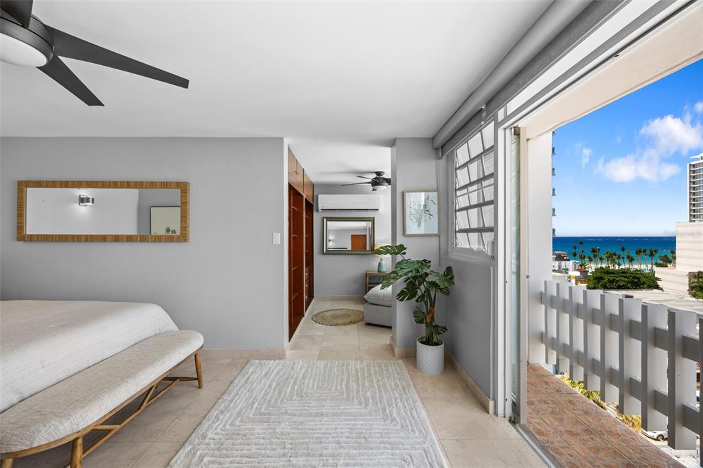 A bedroom with a balcony overlooking the ocean, featuring light tile floors and wood cabinetry — 1126 ASHFORD AVENUE UNIT 88, SAN JUAN, PR