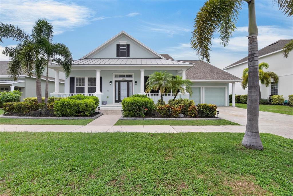 A light blue single-story house features a front porch, metal roof, and palm trees — 5246 BRIGHTON SHORE DRIVE, APOLLO BEACH, FL