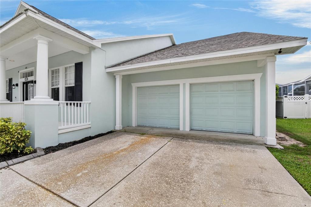A light blue house exterior features a two-car garage and a covered front porch — 5246 BRIGHTON SHORE DRIVE, APOLLO BEACH, FL