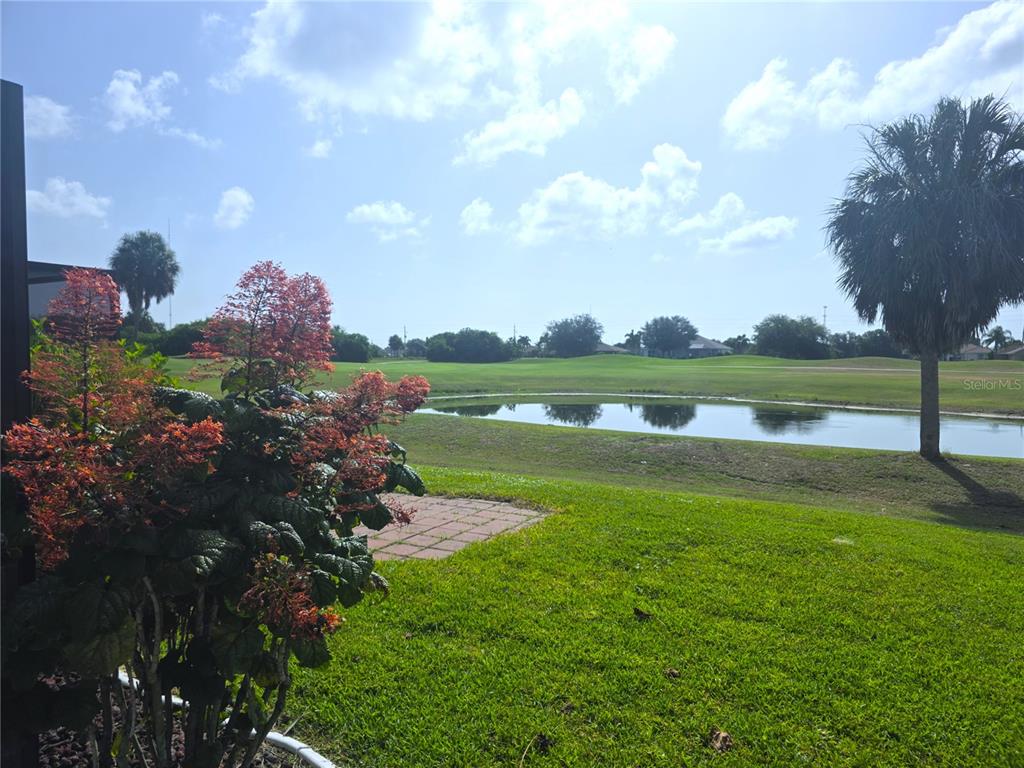 A bright red front door with glass sidelights sits on a tiled porch — 20 MEDALIST COURT, ROTONDA WEST, FL