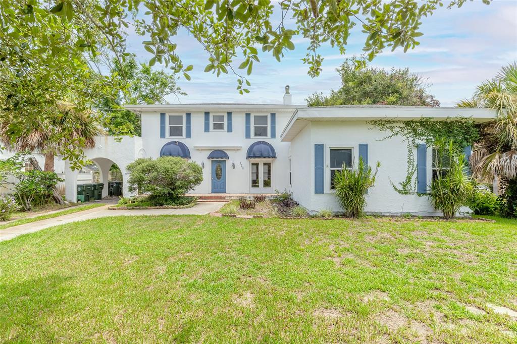 A two-story white house with blue shutters and a covered entryway sits on a lawn — 724 N OLEANDER AVENUE, DAYTONA BEACH, FL