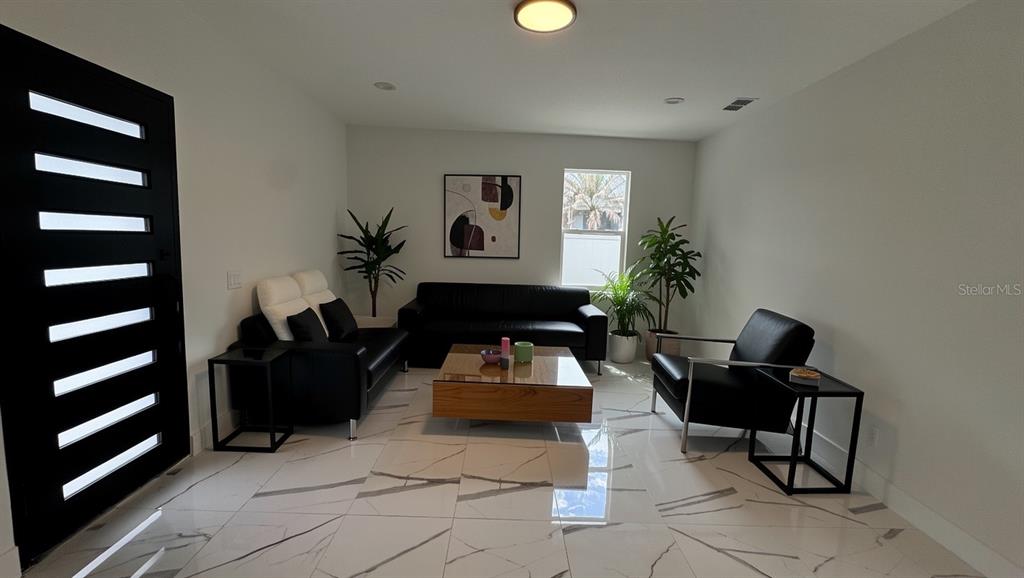 A living room features black leather furniture, a wooden coffee table, and white marble flooring — 27 W 8TH STREET, APOPKA, FL