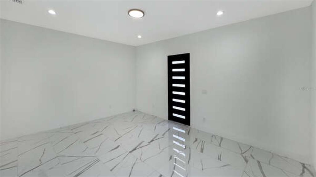 An empty room features white walls, recessed lighting, and white marble-patterned tile flooring — 27 W 8TH STREET, APOPKA, FL