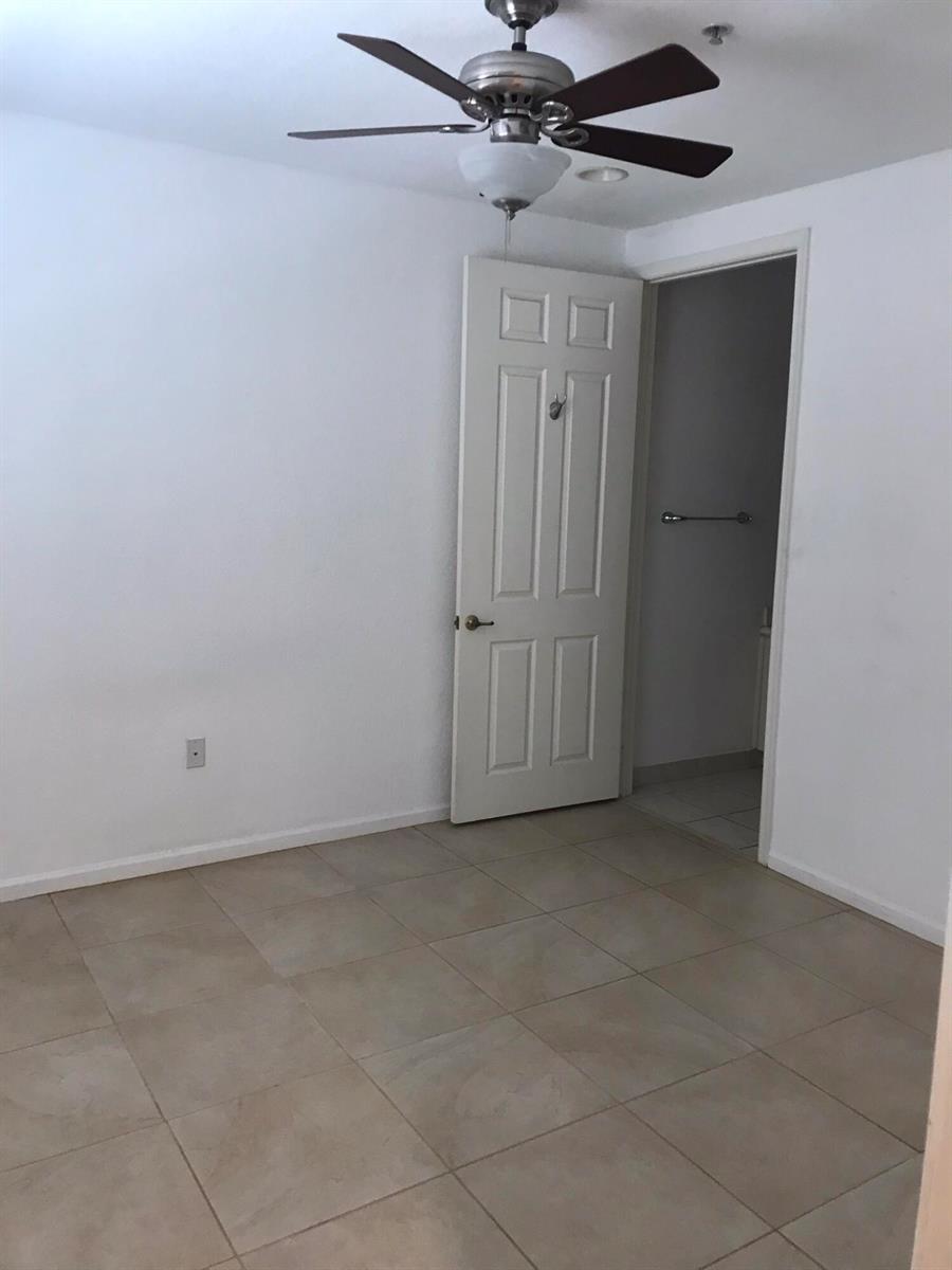 An empty room features white walls, beige tile flooring, a ceiling fan, and an open door — 1430 Via Alferi, Boynton Beach FL 33426, BOYNTON BEACH, FL