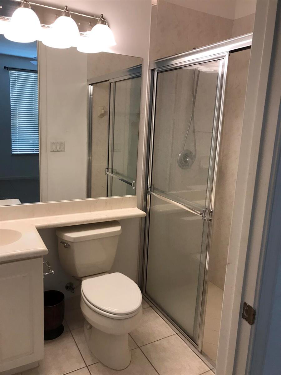A bathroom features a vanity, a toilet, and a glass-enclosed shower with tiled walls — 1430 Via Alferi, Boynton Beach FL 33426, BOYNTON BEACH, FL