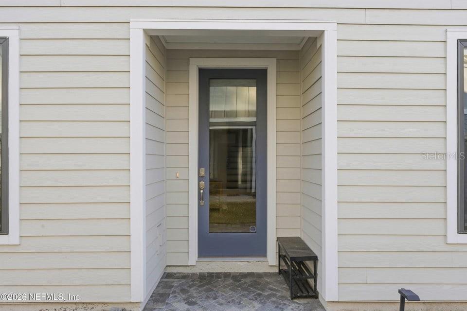 A blue front door with a glass panel is centered on a light-colored siding exterior — 10023 FILAMENT BOULEVARD, JACKSONVILLE, FL