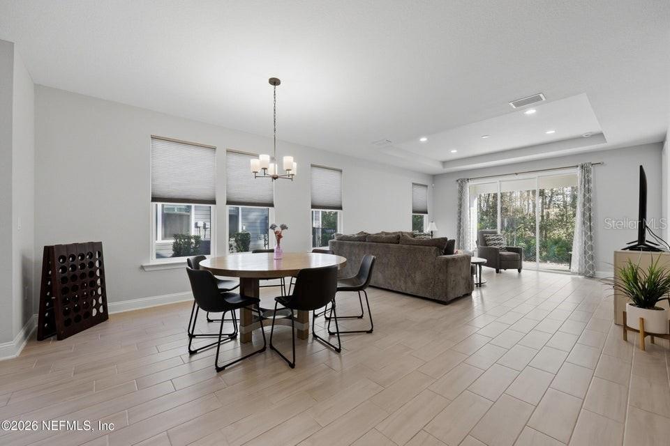 A dining area and living room with light tile floors, neutral walls, and large windows — 10023 FILAMENT BOULEVARD, JACKSONVILLE, FL