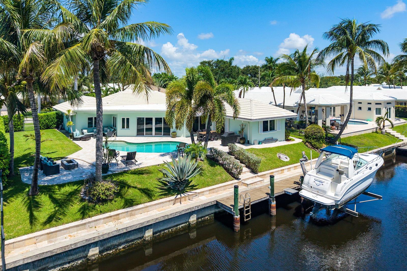 An aerial view of a waterfront house with a pool, patio, and boat lift — 940 SW Mulberry Way, Boca Raton FL 33486, BOCA RATON, FL
