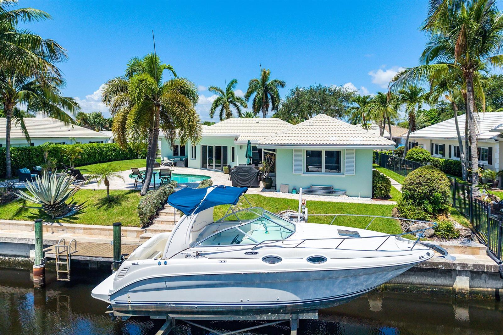An aerial view of a waterfront house with a pool and a boat on a lift — 940 SW Mulberry Way, Boca Raton FL 33486, BOCA RATON, FL