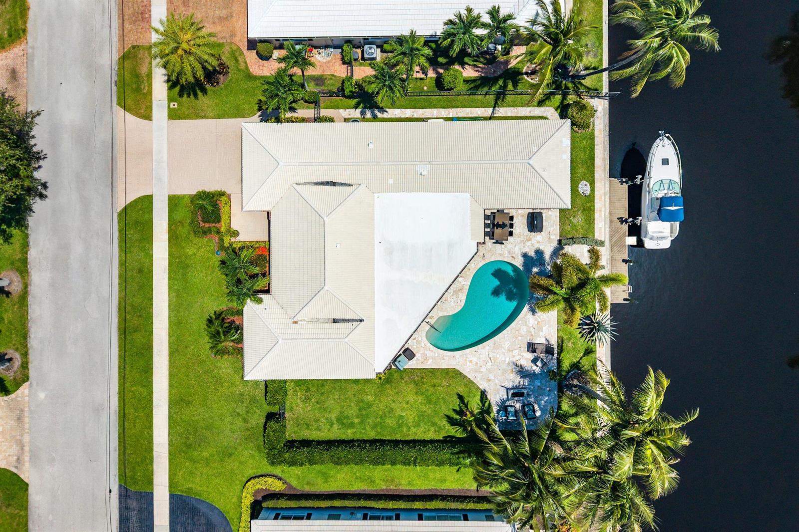 An aerial view shows a house with a pool, patio, and boat docked on a canal — 940 SW Mulberry Way, Boca Raton FL 33486, BOCA RATON, FL