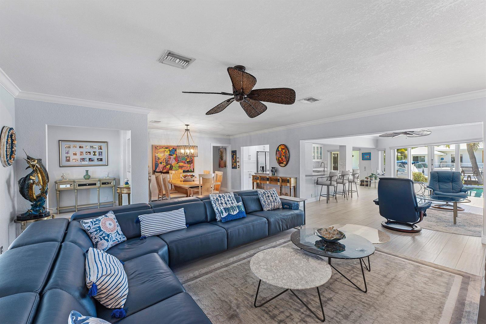 A spacious living room features a blue sectional sofa, two coffee tables, and an open kitchen — 940 SW Mulberry Way, Boca Raton FL 33486, BOCA RATON, FL