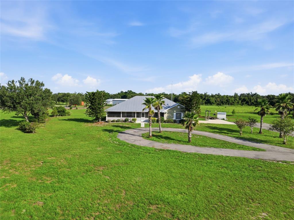 An aerial view shows a single-story house with a metal roof and wraparound porch — 1277 SW EAST CREEK TRAIL, ARCADIA, FL