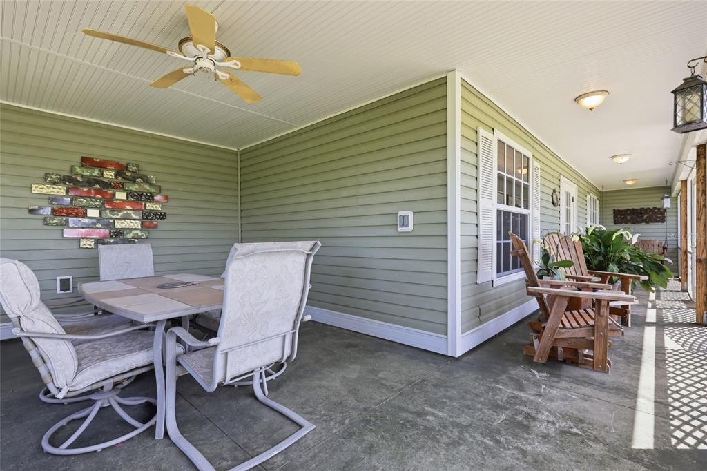 A covered porch features light green siding, a ceiling fan, and outdoor furniture — 1277 SW EAST CREEK TRAIL, ARCADIA, FL