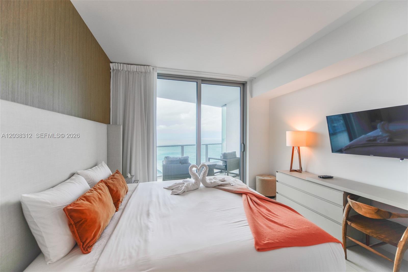 A modern bedroom features a bed with towel swans, a desk, and a balcony view — 4111 S Ocean Dr # 3204, Hollywood FL 33019, HOLLYWOOD, FL