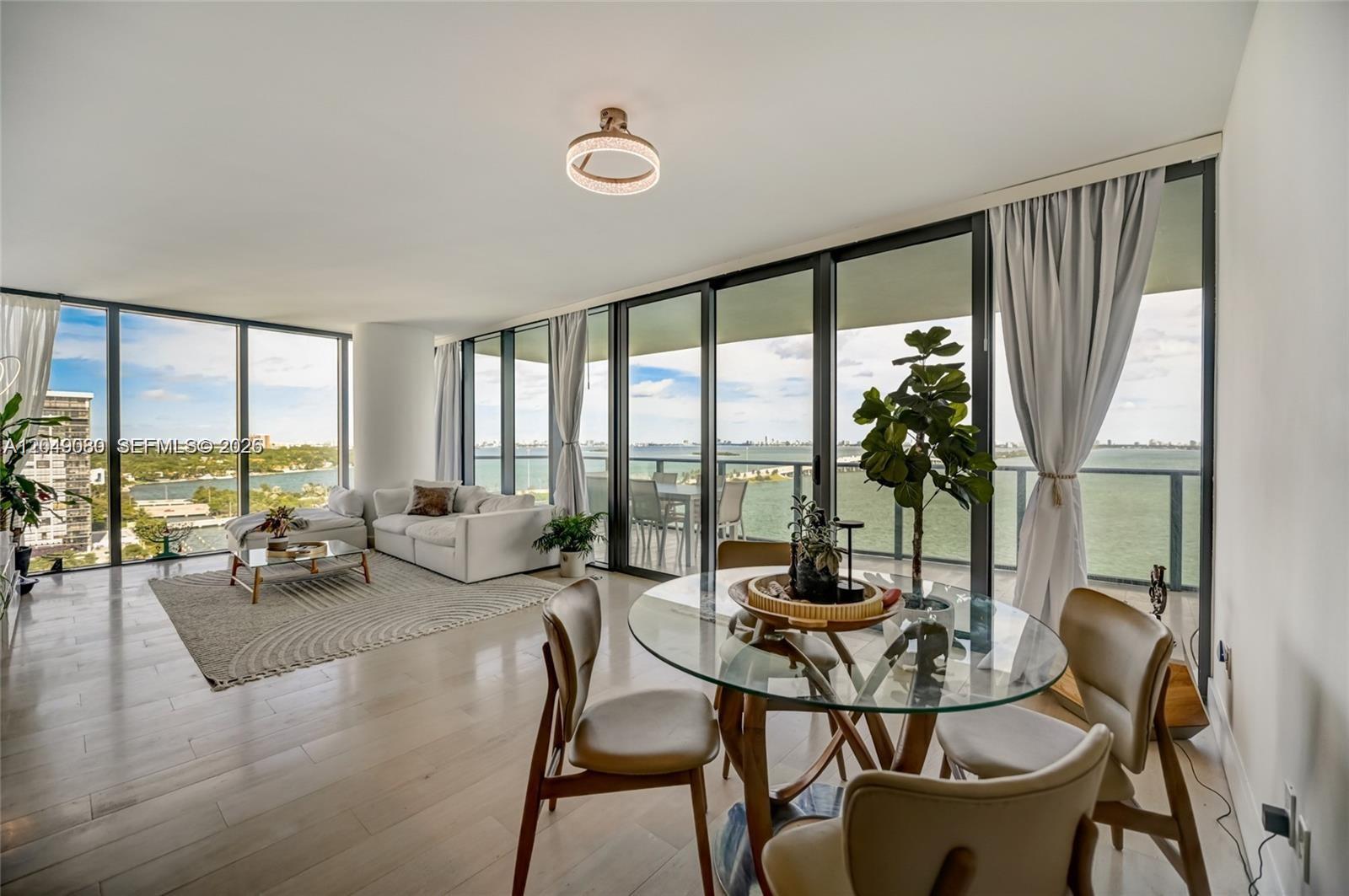 A bright living and dining area features floor-to-ceiling windows with expansive water views — 3131 NE 7th Ave # 1806, Miami FL 33137, MIAMI, FL