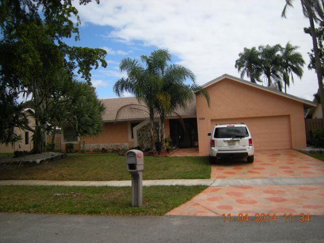 A single-story house with a tan exterior, a two-car garage, and a palm tree — 7035 NW 49th Place, Lauderhill FL 33319, LAUDERHILL, FL