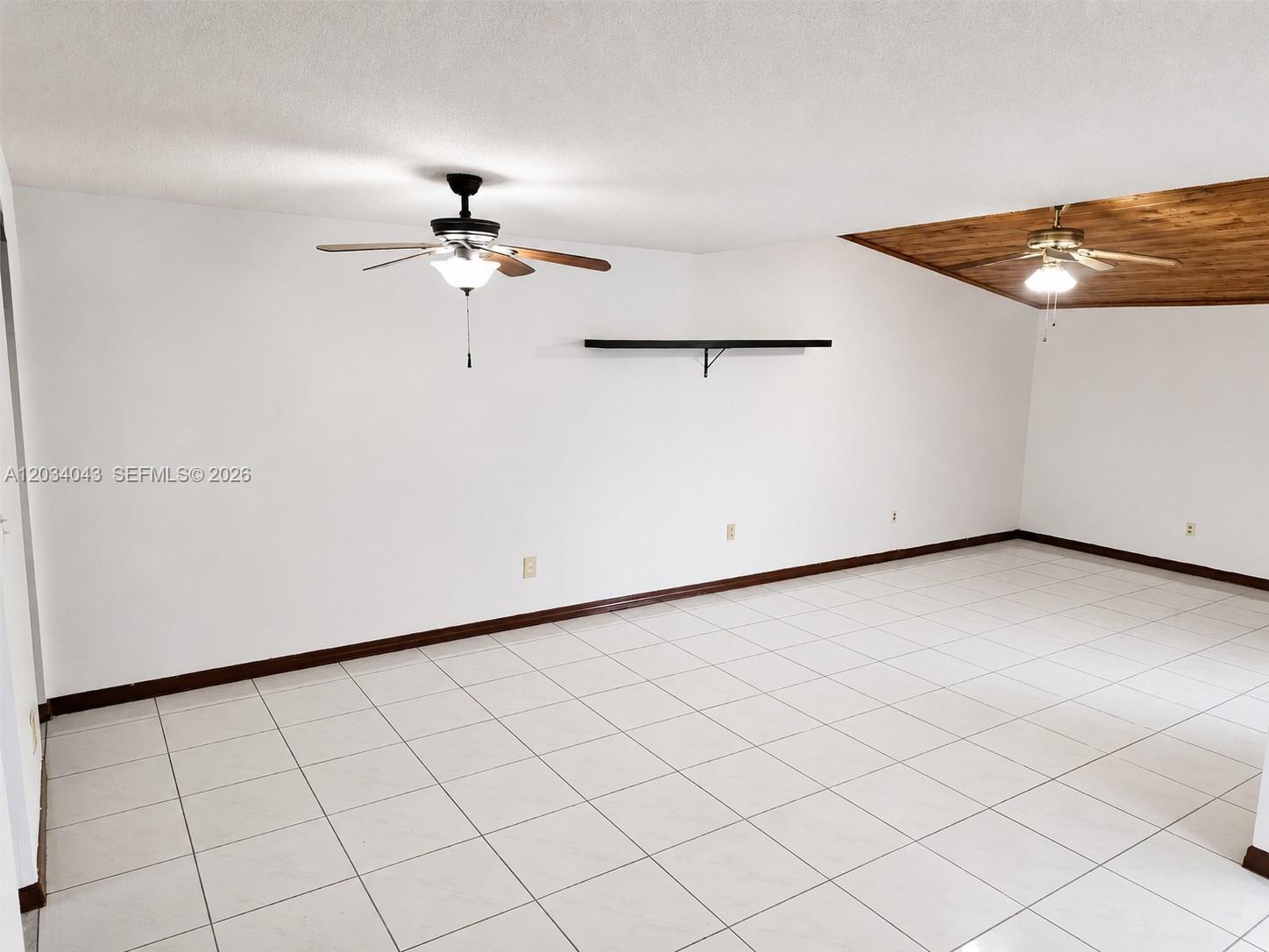 An empty room features white tile floors, white walls, two ceiling fans, and a wood-paneled ceiling — 6521 SW 114th Ave, Miami FL 33173, MIAMI, FL