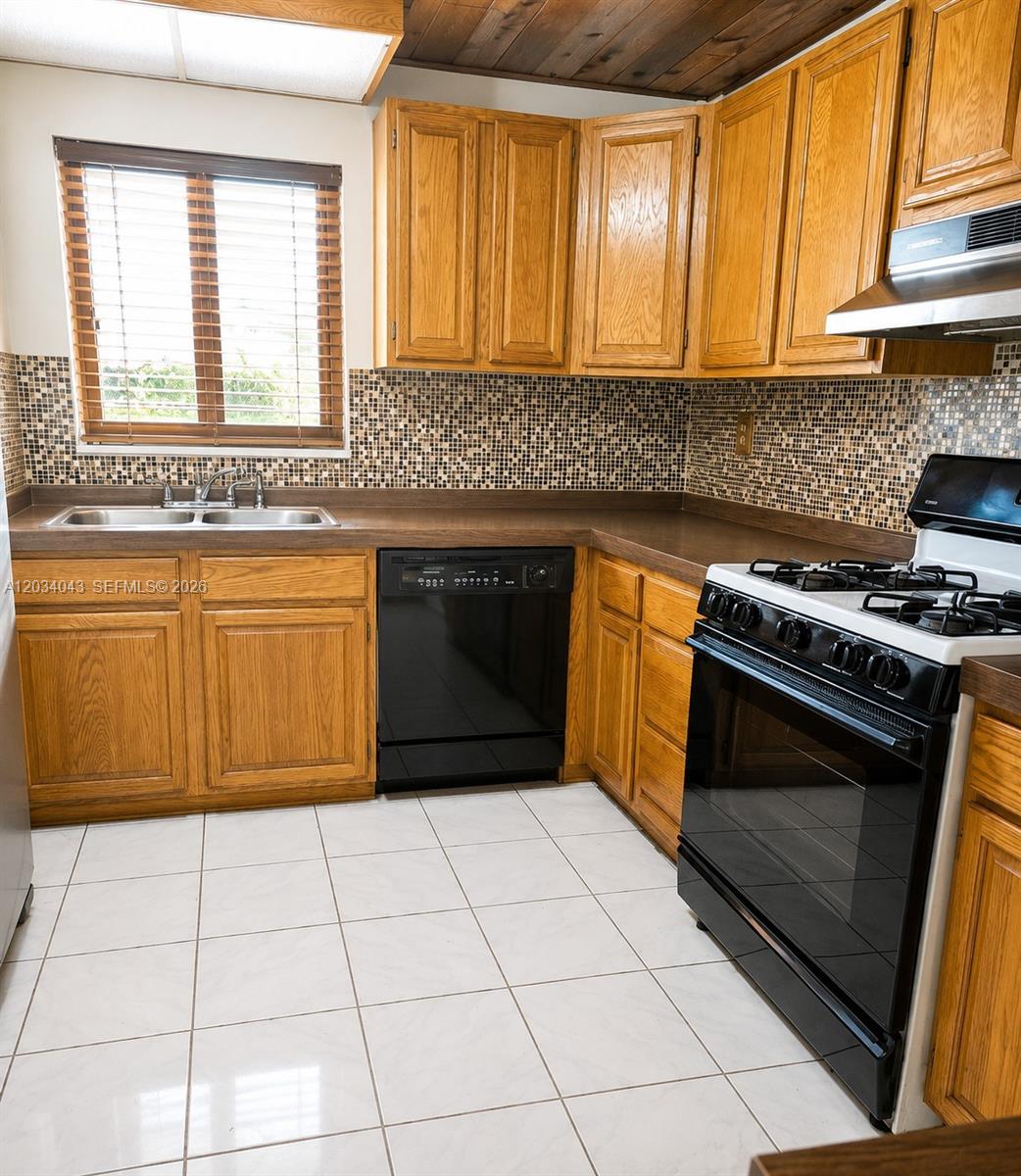 A kitchen features oak cabinets, a mosaic tile backsplash, white floor tiles, and black appliances — 6521 SW 114th Ave, Miami FL 33173, MIAMI, FL