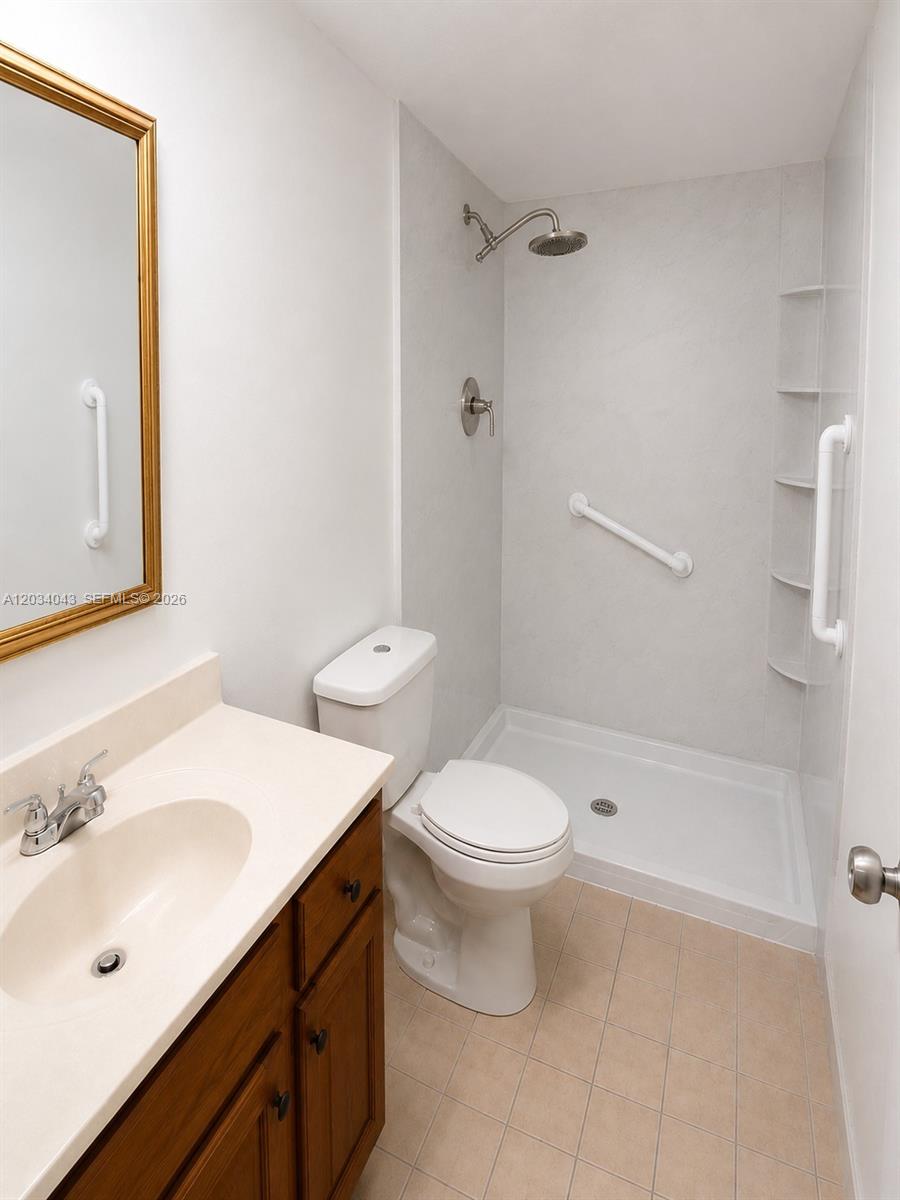 A bathroom features a wooden vanity, a toilet, and a walk-in shower with grab bars — 6521 SW 114th Ave, Miami FL 33173, MIAMI, FL