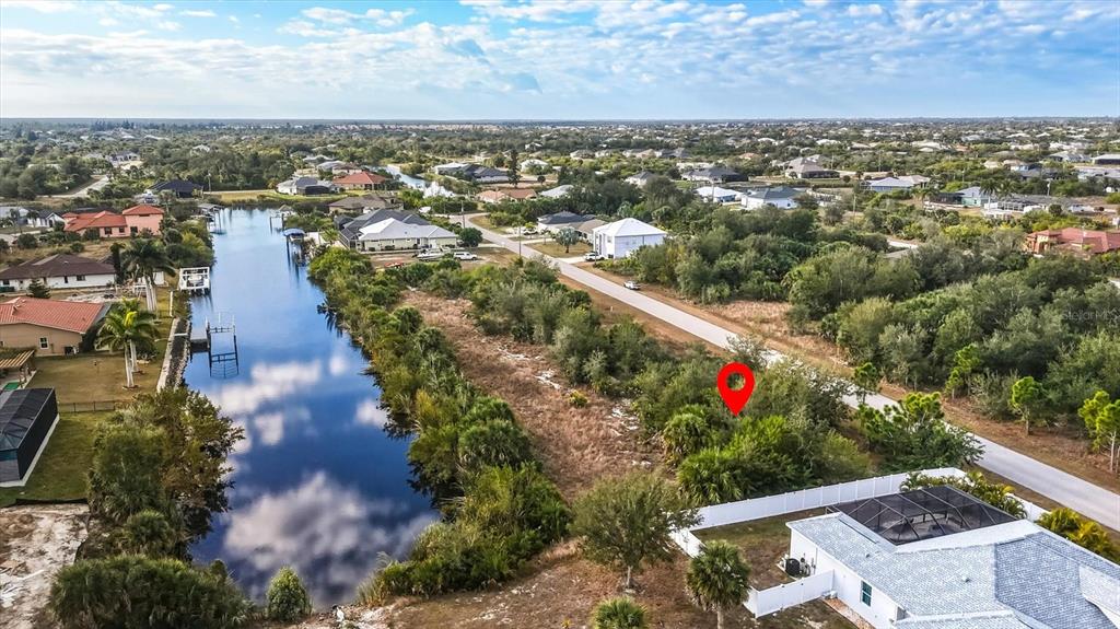 An aerial view shows a vacant lot next to a canal and residential houses — 9484 NASTRAND CIRCLE, PORT CHARLOTTE, FL
