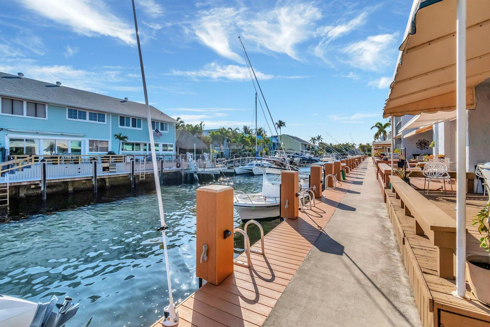 A concrete dock with wooden posts runs alongside a canal lined with boats and houses — 732 NE 12th Terrace # 6, Boynton Beach FL 33435, BOYNTON BEACH, FL