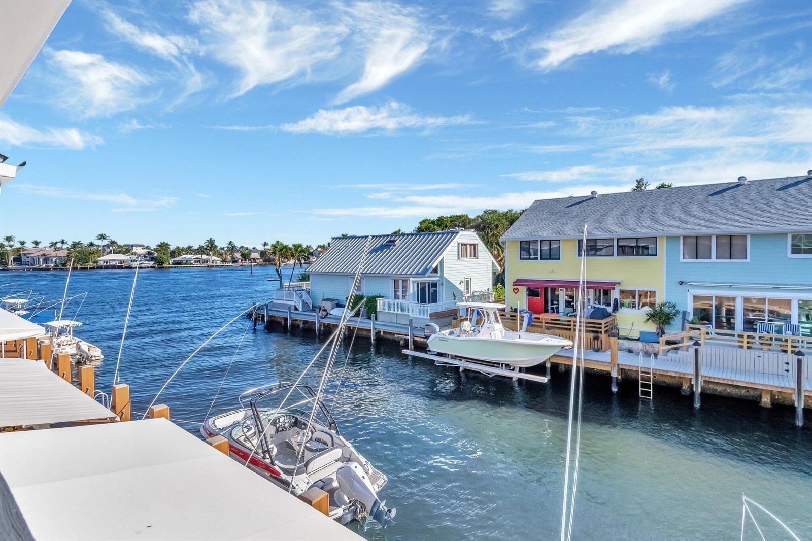 A view of a canal with docked boats and colorful waterfront houses under a blue sky — 732 NE 12th Terrace # 6, Boynton Beach FL 33435, BOYNTON BEACH, FL
