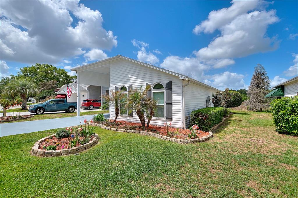 A white single-story house with a carport, arched windows, and a landscaped front yard — 1083 MOTORCOACH DRIVE, POLK CITY, FL