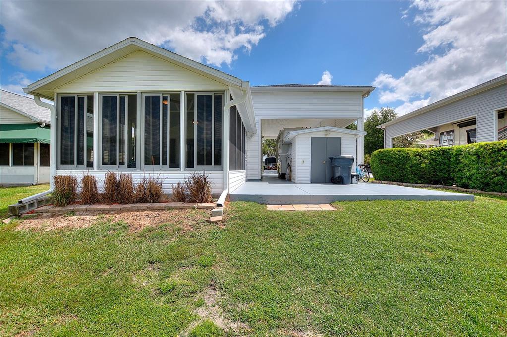 A white house with a screened-in porch, a carport, and a concrete patio area — 1083 MOTORCOACH DRIVE, POLK CITY, FL