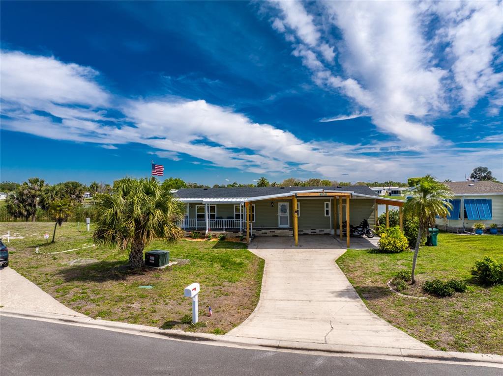 A single-story house with a concrete driveway, a covered carport, and a front porch — 6115 SHEARWATER DRIVE, ENGLEWOOD, FL