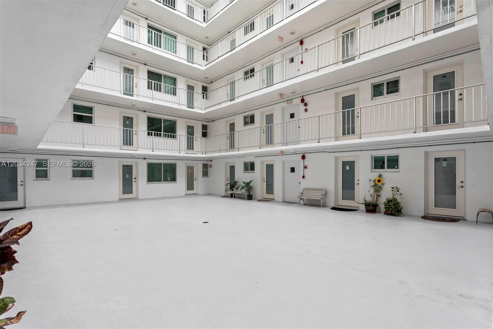 An open-air courtyard surrounded by a multi-story apartment building with white exterior walls — 1820 James Ave # 2F, Miami Beach FL 33139, MIAMI BEACH, FL