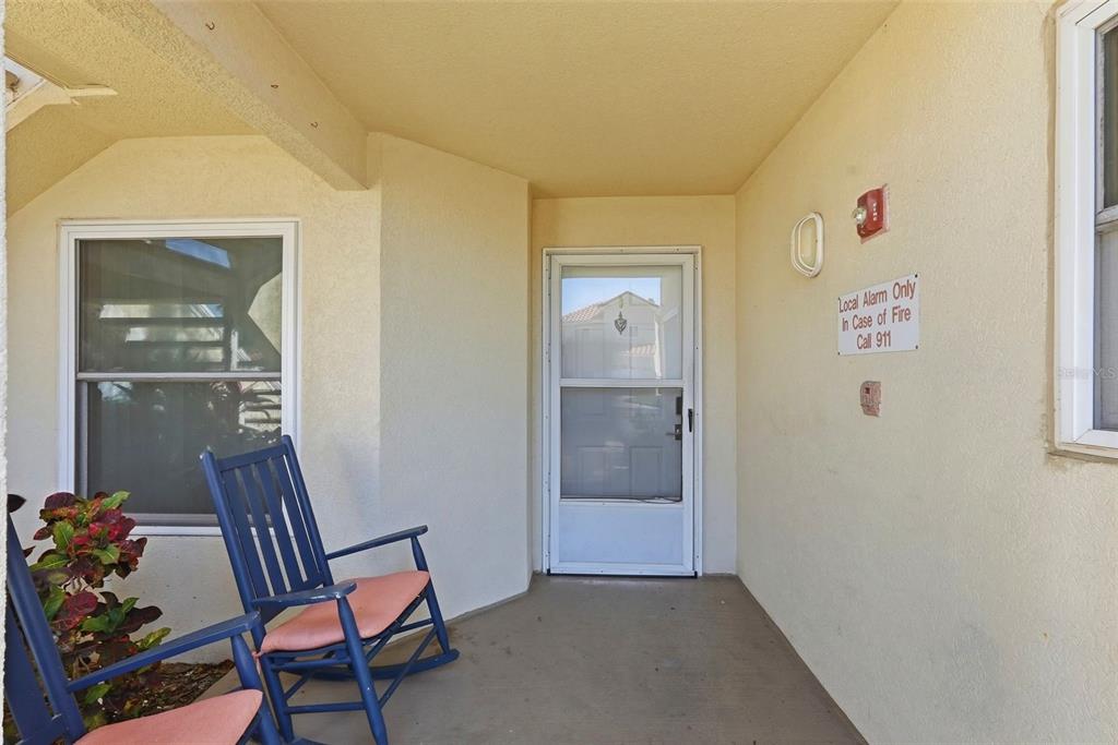 A covered porch features a blue rocking chair, a screen door, and a fire alarm sign — 6151 BAHIA DEL MAR BOULEVARD UNIT 123, ST PETERSBURG, FL