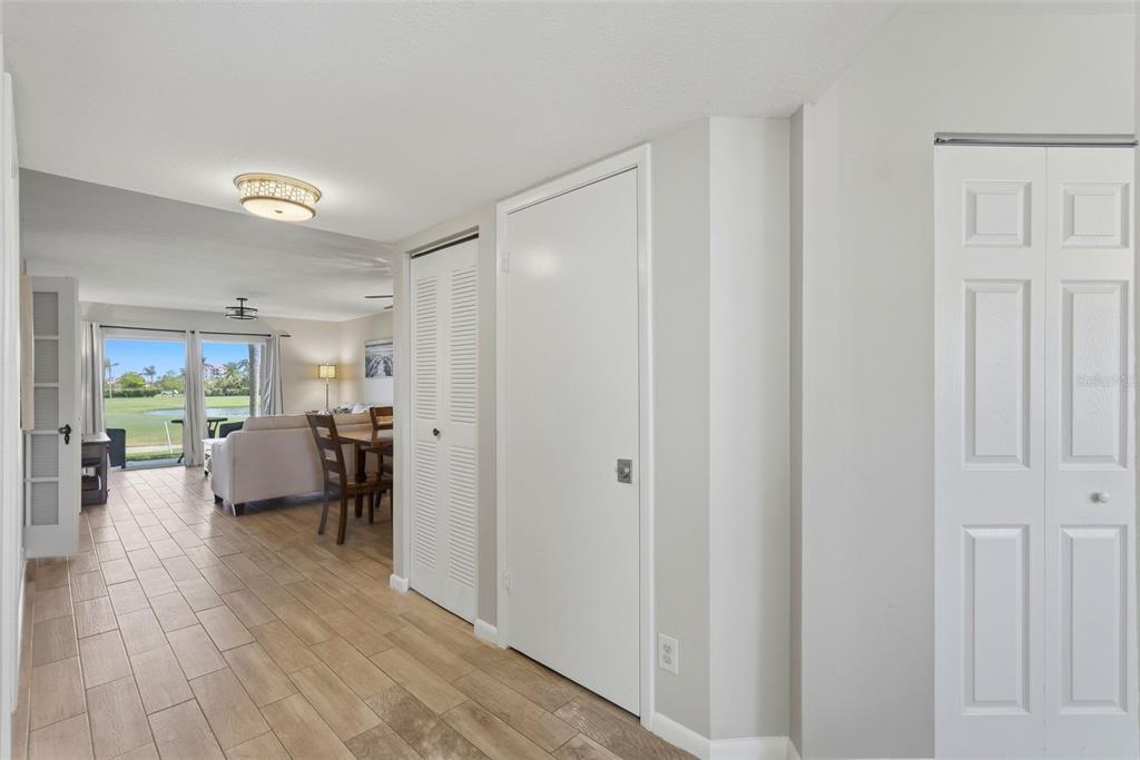 A hallway with light wood-look tile flooring leads to a living area with a view — 6151 BAHIA DEL MAR BOULEVARD UNIT 123, ST PETERSBURG, FL