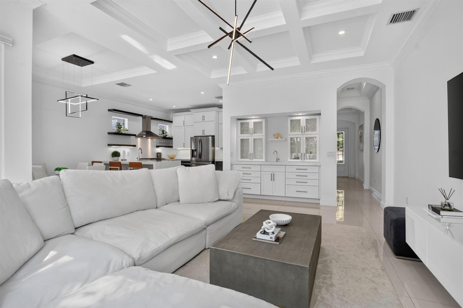 A bright, open-concept living room features a white sectional, coffered ceilings, and a wet bar — 500 NE Wavecrest Way, Boca Raton FL 33432, BOCA RATON, FL