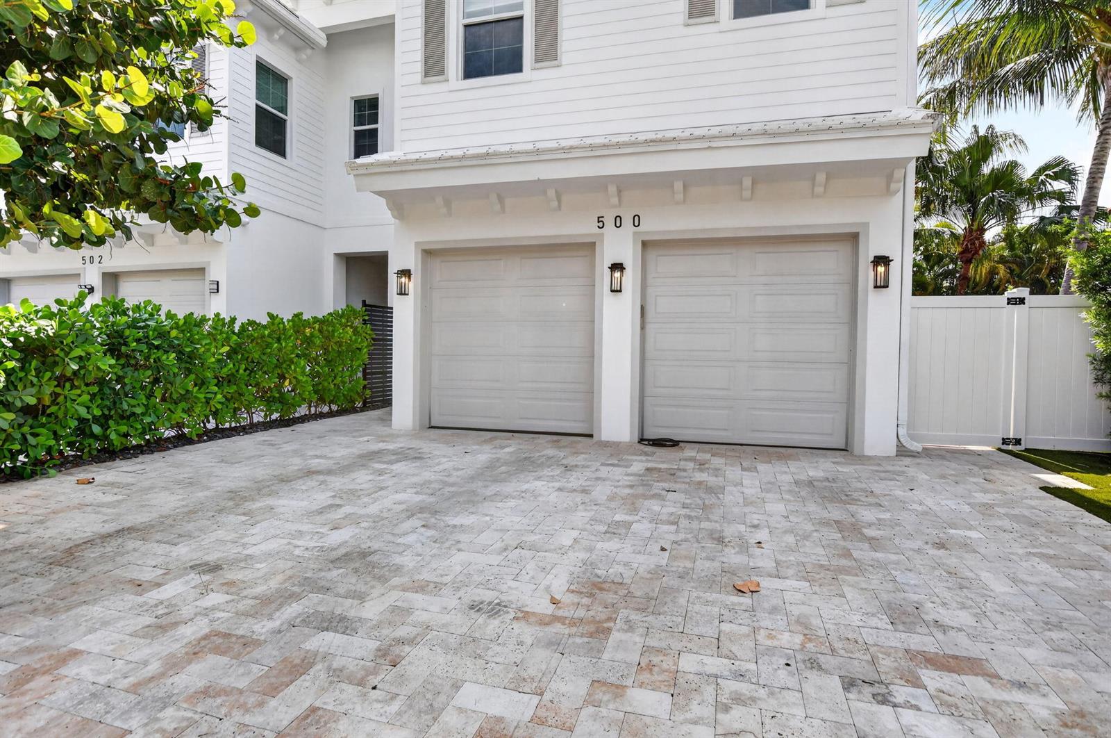 A two-car garage with light-colored doors and a paved driveway in front of a house — 500 NE Wavecrest Way, Boca Raton FL 33432, BOCA RATON, FL